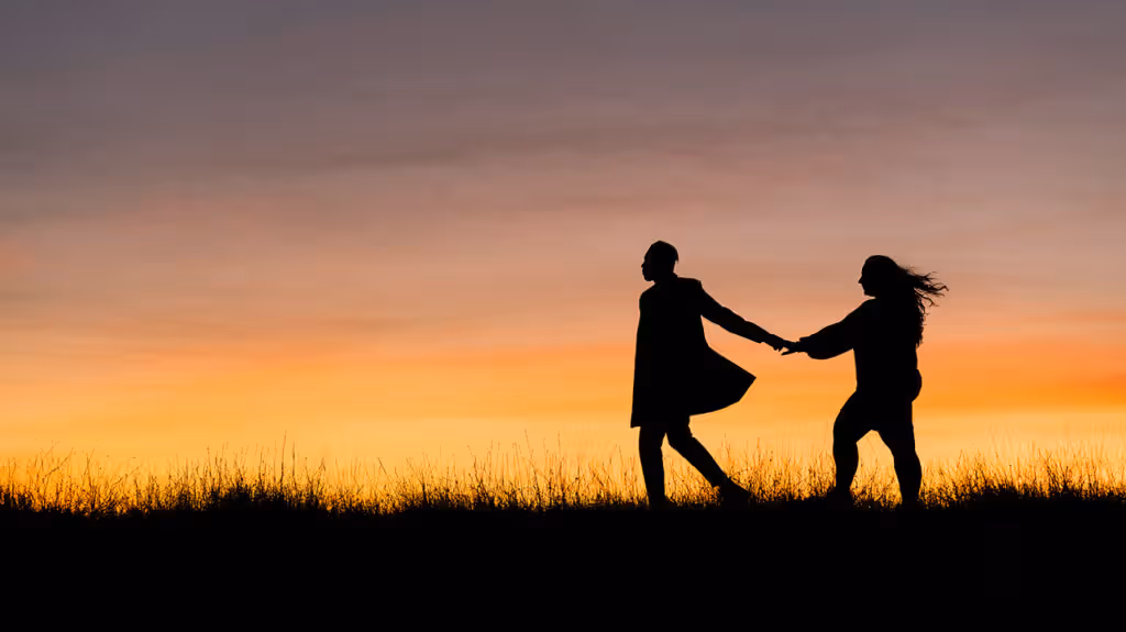 couple silhouette sunset holding hands walking grass 1296x728 header 1024x575 1